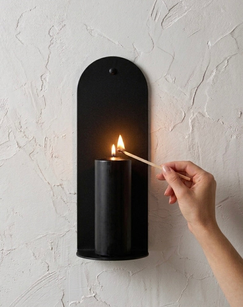 Close-up of Black Ink Bold wall sconce with hand lighting candle, Nomad Studio