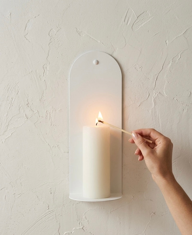 Close-up of Bone White Bold wall sconce with hand lighting candle, Nomad Studio. 